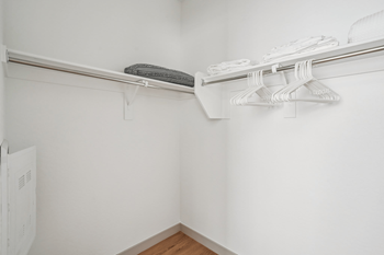 A white wall with a clothes rack and a white paper leaning against it.